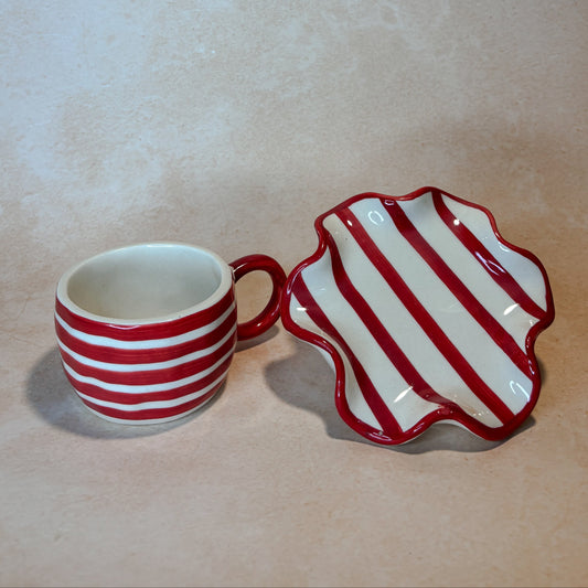 Red and white striped mug and dish on a beige background